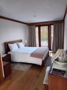 - une chambre avec un grand lit blanc et du parquet dans l'établissement Eira das Caldas, à Caldelas