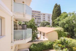 an apartment building with a balcony and trees at Bel Appartement Juan les Pins in Antibes