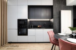 a kitchen with white cabinets and black appliances at Topaz - Infinity Pool & Spa Resort in Mamaia Nord