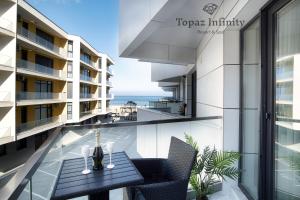 Topaz - Infinity Pool & Spa Resort في مامايا نورد نافورداي: شرفة مع طاولة وكراسي والمحيط