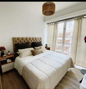 ein Schlafzimmer mit einem großen Bett und einem großen Fenster in der Unterkunft Departamento Güemes in Mar del Plata