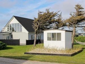 een wit huis met een zwart dak bij 14 person holiday home in L kken in Løkken