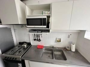 a small kitchen with a sink and a microwave at Depto Impecable Alvear! in Azul