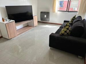 a living room with a black couch and a flat screen tv at Depto Impecable Alvear! in Azul