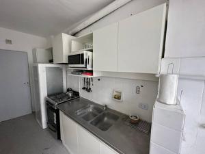 a small kitchen with white cabinets and a sink at Depto Impecable Alvear! in Azul +14 photos