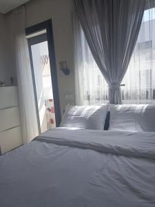 - une chambre avec un lit blanc et une fenêtre dans l'établissement La Gironde - Sweet Home - Casablanca, à Casablanca