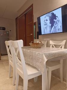 mesa de comedor blanca con sillas blancas y TV en La Gironde - Sweet Home - Casablanca, en Casablanca