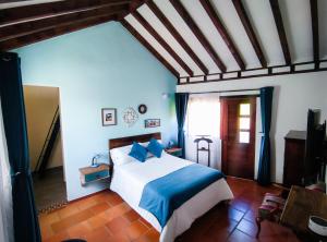 a bedroom with a large bed with blue pillows at Casa El Retiro - Villa de Leyva in Villa de Leyva