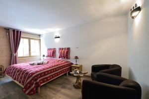 a bedroom with a bed and a chair and a window at Hotel Les Mélèzes in Haudères