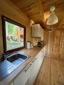 - une cuisine avec évier et une fenêtre dans une cabine dans l'établissement Domek Letniskowy nad Jeziorem, Las, Mazury, à Wiartel Mały