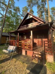 une cabane dans les bois avec une terrasse couverte dans l'établissement Domek Letniskowy nad Jeziorem, Las, Mazury, à Wiartel Mały