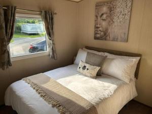 a bed sitting in a bedroom with a window at Tarka Holiday Park - Summer Breeze - Coastal Breaks - North Devon - Braunton-Barnstaple in Ashford