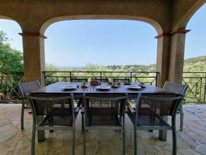 drewniany stół i krzesła na patio w obiekcie Le Jardin des Olives w mieście Caunes-Minervois