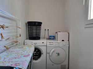 a laundry room with a washing machine and a washer at Le Jardin des Olives in Caunes-Minervois