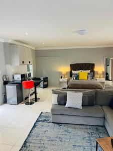 a bedroom with a bed and a couch and a kitchen at OneOnArumAvenue in Johannesburg