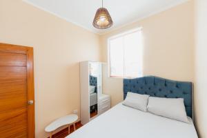 Schlafzimmer mit einem Bett mit blauem Kopfteil und einem Fenster in der Unterkunft Edificio Rojo Departamentos. in Tarapoto
