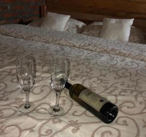 Una botella de vino en una cama con dos copas en Vila Ivona en Čačak