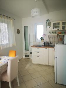 kuchnia z białymi szafkami, stołem i lodówką w obiekcie Apartments Prosperina Hvar w Hvarze