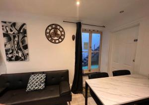 a living room with a couch and a clock on the wall at Modern Appartment in London