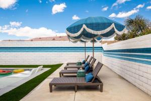 een patio met stoelen, een parasol en een tafel bij Backyard Pool Oasis @ Tropicale Blue in Coachella