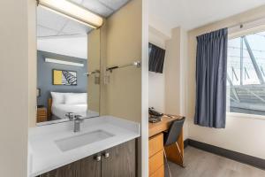 a bathroom with a sink and a bed and a mirror at YWCA Hotel Vancouver in Vancouver