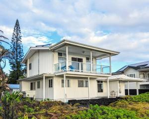a large white house with a balcony on a hill at Maka'Ala Lani - A view of Heaven in Keaau