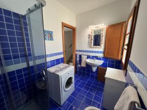 La salle de bains est pourvue de carrelage bleu et d'une douche avec un lave-linge. dans l'établissement Casa delle Conchiglie di Grace, à Porto San Paolo