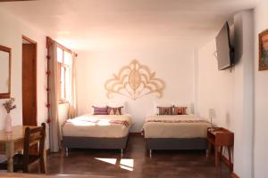 a bedroom with two beds and a table and a window at Astromelia Hotel in Ayacucho