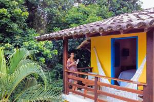 Uma mulher à porta de uma pequena casa. em Pousada Sabina em Barra Grande