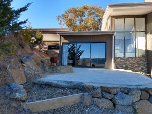 a house with a stone retaining wall and a driveway at Willow Bay Lodge in Jindabyne