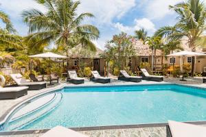 a swimming pool with chaise lounge chairs and palm trees at Hidden Jewel Boutique Hotel in San Pedro