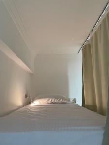 a white bed in a white bedroom with a window at Serafy City Center Hostel and Pool for Foreigners Adults Only in Hurghada