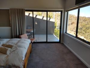 a bedroom with a bed and a large window at Willow Bay Lodge in Jindabyne