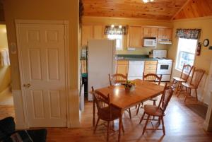 eine Küche mit einem Tisch und Stühlen sowie einem Kühlschrank in der Unterkunft Brudenell Fairway Chalets in Georgetown