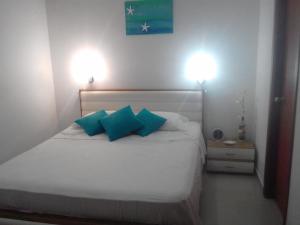 a bedroom with a white bed with two blue pillows at Costa Azul Apto603 in Playa Dormida +8 photos