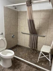 a bathroom with a shower with a toilet and a chair at Regal 8 Inn & Suites in Lincoln