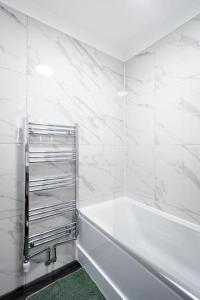 een witte badkamer met een bad en een groen tapijt bij Paddington House in Londen