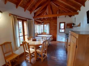 cocina y comedor con mesa y sillas en Cabañas Chapelco en San Martín de los Andes