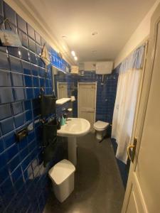 Baño de azulejos azules con aseo y lavamanos en casa contessa rinaldi, en Bolonia