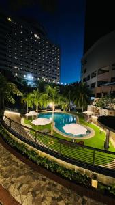 ナゴヤにあるGrand Eska Hotel & Suites Batamの夜間の公園内のスイミングプール(パラソル付)