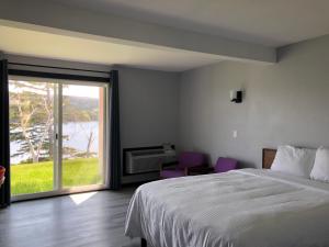 a bedroom with a bed and a large sliding glass door at Duck Cove Inn in Margaree Harbour