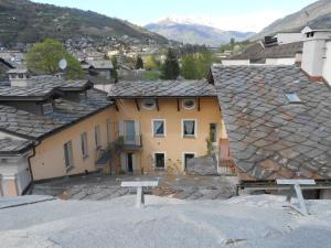 a yellow house with a slate roof in a city at Casa De Giorgis in Aosta