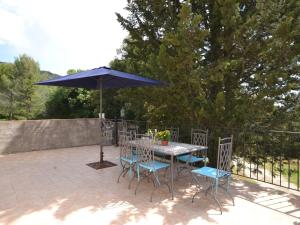 een tafel en stoelen met een parasol op een patio bij Flat with private pool in the heart of nature in Malaucène