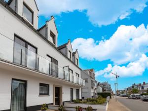 a row of white houses on a street with a blue sky at Beautiful renovated studio in Zeebrugge on the beach in Zeebrugge