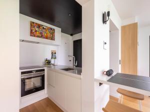 uma cozinha com armários brancos e um lavatório em Beautiful renovated studio in Zeebrugge on the beach em Zeebrugge