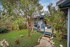 a house with a yard with a tree and a bench at Calm 3922 in Surf Beach