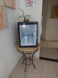 een televisie zittend op een tafel met flessen water erin bij Hotel Dublin in Araraquara