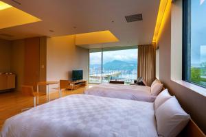 a hotel room with two beds and a large window at Garden Terrace Nagasaki Hotels & Resorts in Nagasaki