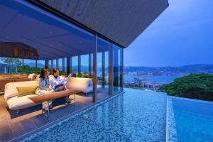 two women sitting on a couch in a house with a pool at Garden Terrace Nagasaki Hotel & Resort in Nagasaki