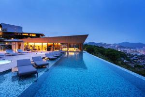 uma piscina com espreguiçadeiras num edifício em Garden Terrace Nagasaki Hotel & Resort em Nagasaki